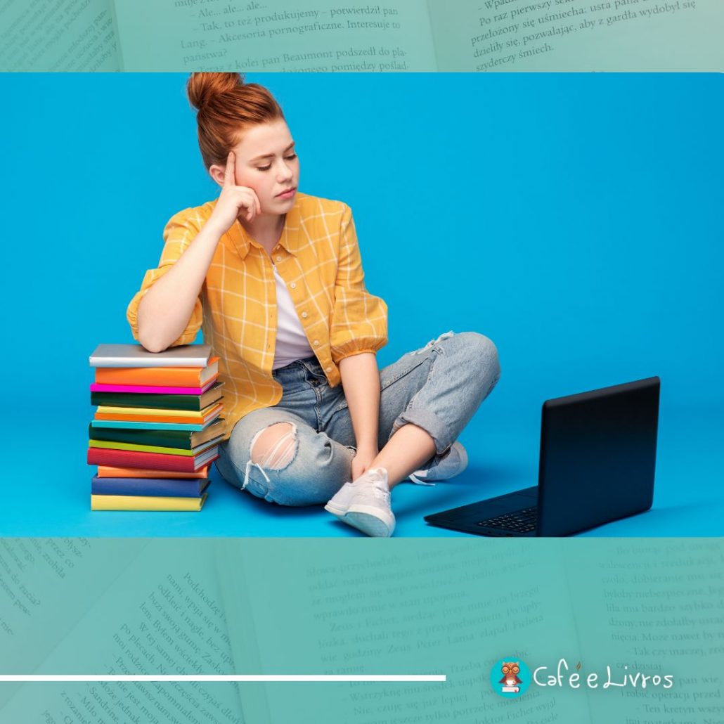 Garota ruiva, sentada no chão, de frente para o computador e usando uma pilha de livros como apoio de braço